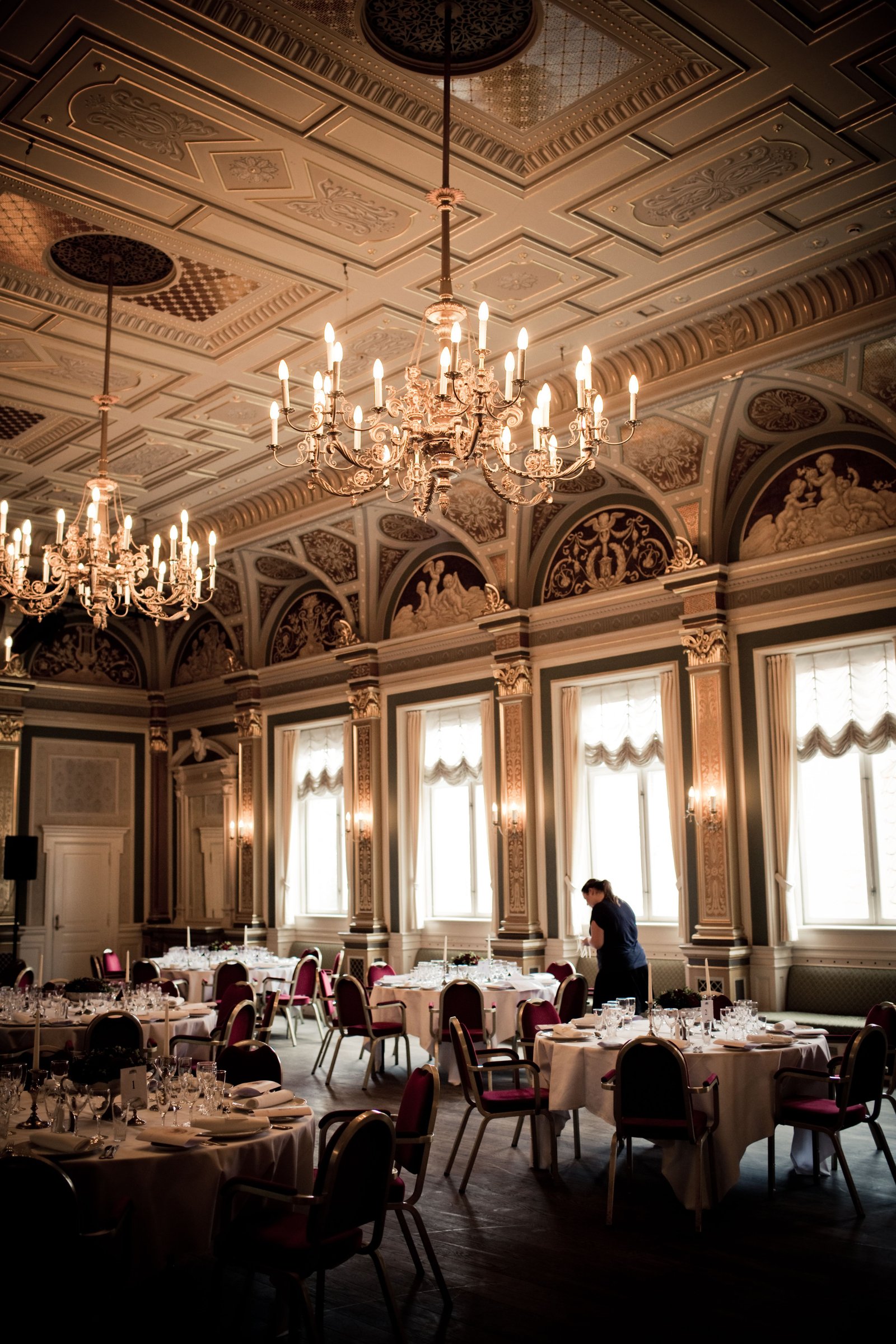 Elegant chandelier-lit dining room with ornate ceiling and fine table settings